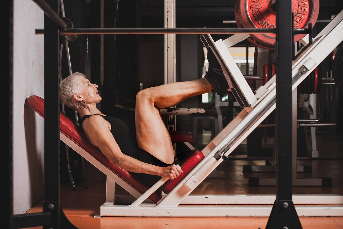 Older woman exercising on a leg press machine at a gym